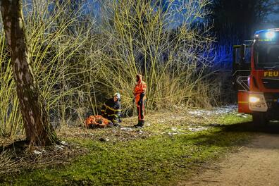 Eine gerettete Person wird von den Einsatzkräften betreut. Sie war am Rand vom Teich eingebrochen.