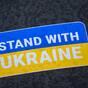 „Stand with Ukraine" steht auf einem Aufkleber in den Landesfarben der Ukraine.