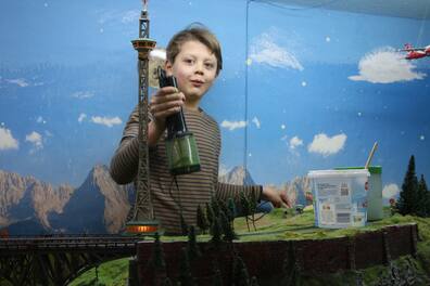 Train-Kids Eutin: Till (9) baut mit einem Grasmaster an einem Stück der Landschaft. Die Grasteile im Gerät sind statisch aufgeladen und stellen sich beim Verteilen auf wie richtiges Gras.